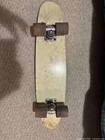Top view of skateboard showing cream deck, trucks, wheels