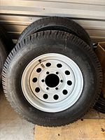 Two mounted trailer wheels leaning against wall