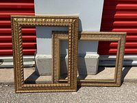 Both ornate gold frames leaning against wall