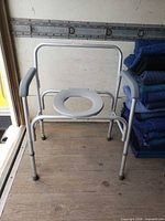 Front angled view of commode chair showing overall structure and adjustable legs