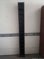 Full view of tall narrow black shelving unit