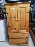 Front view of pine pantry cabinet with doors closed showing overall form and hardware