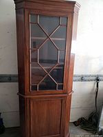 Front view of wood corner cabinet showing glass door and lower panel door