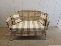 Front view of wicker loveseat with cushion and pillows