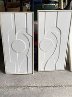 Two of the framed white abstract panels standing side by side