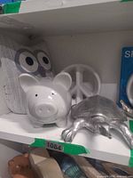 Shelf view showing piggy bank, owl doorstop, peace symbol, partial turtle