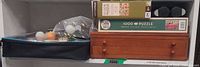 Shelf view showing ping pong case with balls, both puzzle boxes stacked, wooden chess/backgammon box