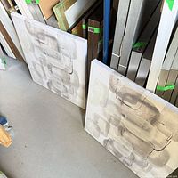 Two identical Bouclair canvas art pieces leaning against shelving