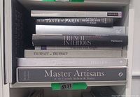 Stack of eight black hardcover books on shelf showing spines and titles