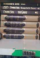 Stack of seven hardcover books: three black dust jackets and four matching beige clothbound volumes
