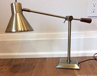 Lamp overall profile on floor showing metal finish, arm, shade, square base