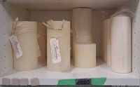 Shelf with eleven ivory and cream pillar candles, some tagged with Soundview label