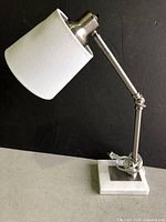 Side view of silver desk lamp with white fabric shade and marble base
