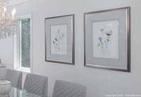 Both framed prints mounted side by side on wall above dining table