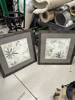 Both framed prints standing on floor showing fronts