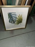 Single framed print featuring monstera and palm leaves, shows frame style and matting