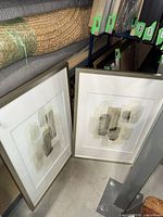 Both framed prints leaning against shelving, showing frames and glazing