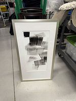 Vertical framed abstract print standing on floor
