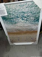 Framed aerial beach ocean print leaning against wall