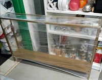 Console table wrapped in plastic showing gold frame and bottom shelf
