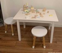 White children’s table with two stools and wooden block toys on top