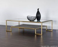 Coffee table staged in empty room, shows full structure with glass top and wood shelf