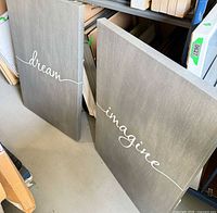 Both canvas artworks leaning against shelf showing front text
