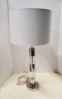 Full view of one lamp showing chrome/lucite column, base, cord and shade
