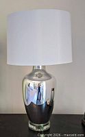 Lamp with white drum shade on dark surface