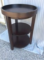 Single round espresso wood end table showing top and shelves