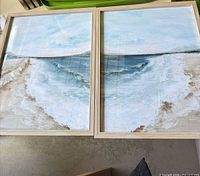 Both framed seascape prints side by side in light wood frames