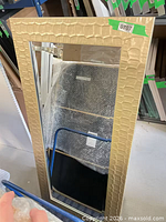 Front view of one gold mirror showing textured frame and reflective surface