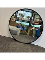 Full view of round mirror leaning against white backdrop