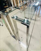 Two chrome and glass console tables in workshop
