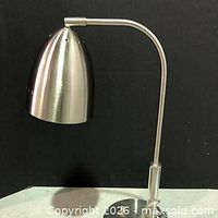 Side view of lamp showing arched arm, dome shade, acrylic accent and base