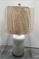 Lamp with shade wrapped in plastic, full view
