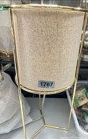 Front view of lamp showing linen shade and gold frame