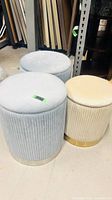 Group shot of two blue and one beige cylindrical storage ottoman stools