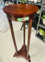 Full view of cherry wood plant stand showing round top, legs and base