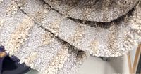 Close-up of rug surface showing loop pile texture and grey/beige colors