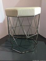 Full view of stool showing white padded seat and chrome geometric base
