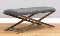 Side profile of grey velvet bench on brass X-frame base