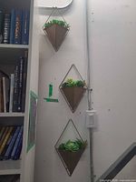 Three matching geometric wall planters mounted vertically on wall