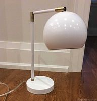 Front view of white desk lamp showing globe shade, arm, stem and base