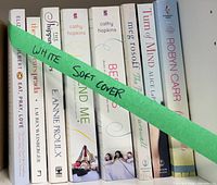 Front view showing all eight white softcover books on shelf