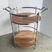 Front view of bar cart showing chrome frame, wood shelves, handles