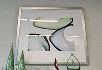Framed abstract artwork hung on wall, showing front view with colors and frame
