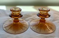 Oblique view of both amber glass candle holders showing shape and color