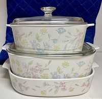 Stacked view of three Corning Ware Pastel Bouquet casseroles with two Pyrex lids