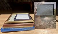 Six assorted picture frames stacked and upright showing finishes and sizes
